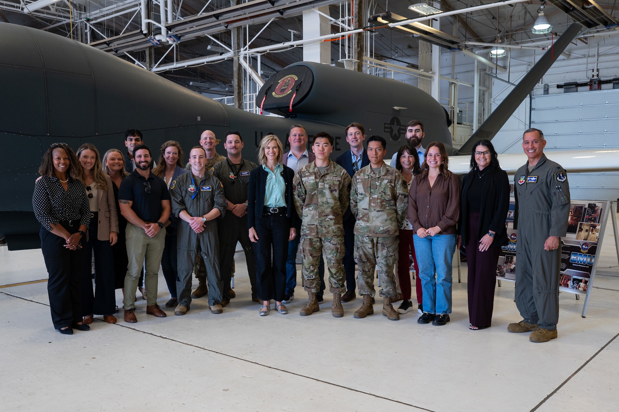 A photo of a group of people standing together in front of a plane in an airplane hangar.