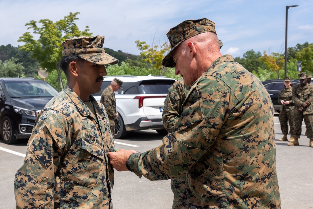 U.S. Navy Petty Officer 2nd Class Daniel Franco Colon, left, a hospital corpsman with 2nd Battalion, 23rd Marine Regiment, forward deployed with 4th Marines, 3rd Marine Division as part of the Unit Deployment Program, stands at attention while Lt. Gen. Roger Turner, commanding general of III Marine Expeditionary Force, presents him with the Navy and Marine Corps Achievement Medal during Korean Marine Exercise Program 25.2 in Camp Mujuk, South Korea, Aug. 7, 2025. KMEP is conducted regularly between the Republic of Korea and U.S. Marine Corps to increase their combined capabilities through realistic training geared towards deterrence and maintaining peace in the Indo-Pacific. Franco Colon is a native of Florida, and Turner is a native of Maryland. (U.S. Marine Corps photo by Cpl. Peter J. Eilen)