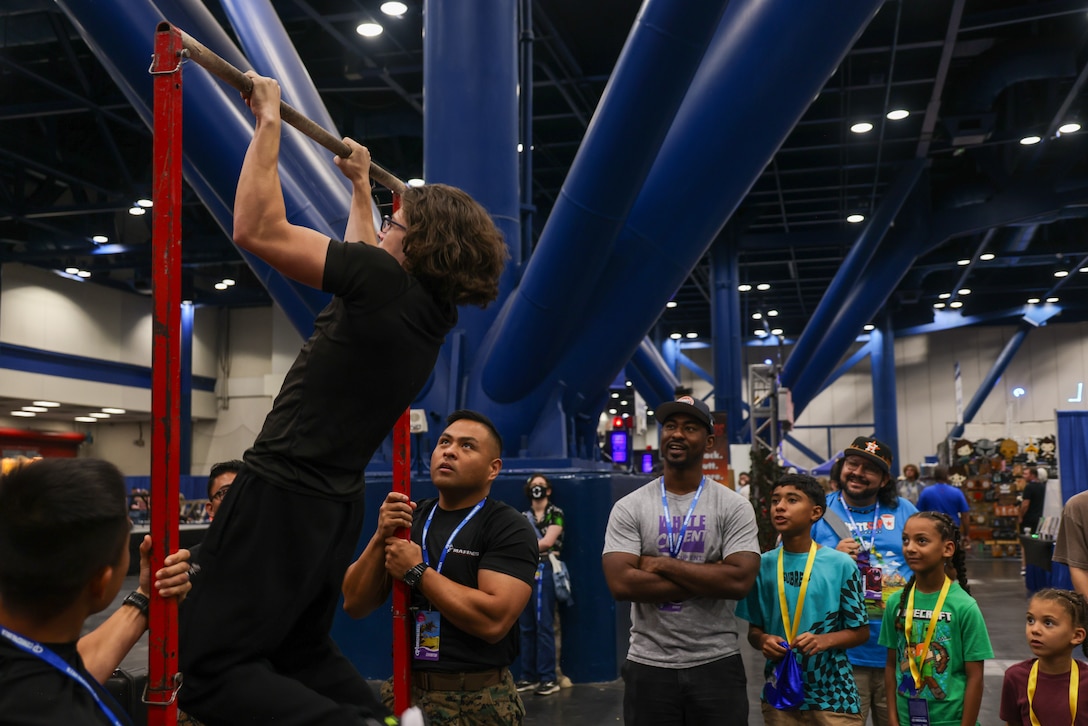An attendee participates in the pull-up bar challenge during Comicpalooza at the George R. Brown Convention Center, in Houston, Texas, June 20-22, 2025. Marines with RS Houston had the opportunity to interact with the community by holding pull-up challenges and utilizing the Marine Battle Position dome, a virtual reality experience that allows users to experience close-quarter combat fighting. (U.S. Marine Corps photo by Sgt. Kree Laing)