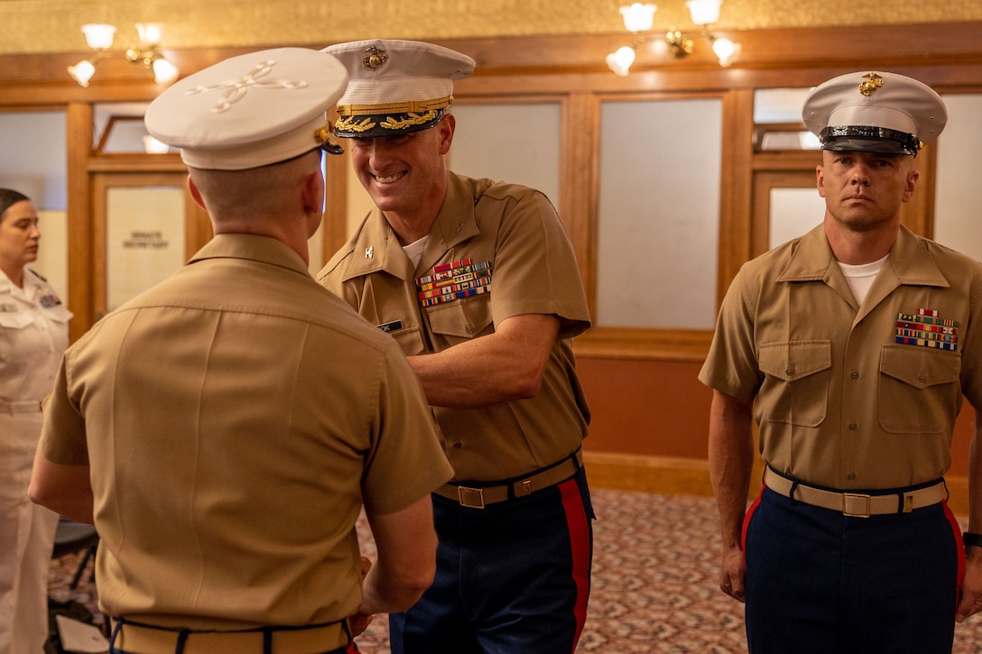 U.S. Marine Corps  Col. Warren Cook, the commanding officer of 8th Marine Corps District, awards Maj. Keegan Kinkade, the outgoing commanding officer, with a meritorious service medal and recruiting ribbon during the Recruiting Station Phoenix change of command ceremony at the Arizona Capitol Museum, Phoenix, Ariz., June 17, 2025.  A change of command ceremony is 
a time-honored tradition that demonstrates the passing of authority and responsibilities from one commanding officer to another. (U.S. Marine Corps photo by Staff. Sgt. Alexis Arend)