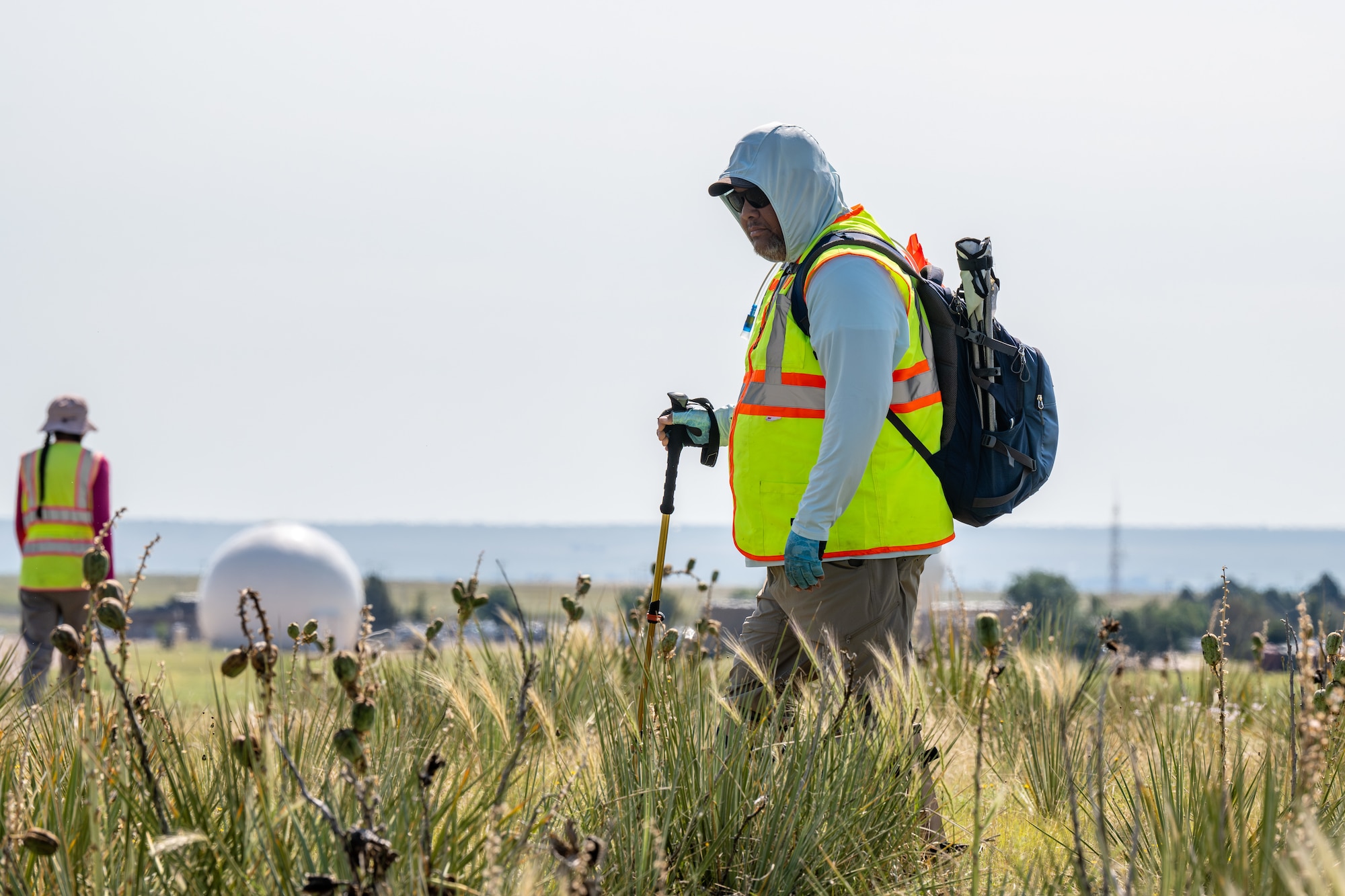 Don Tosee II of the Comanche Nation, Oklahoma, with Jesslin Comanche (Mescalero Apache Tribe of the Mescalero Reservation, New Mexico) in the background, surveys an open space.