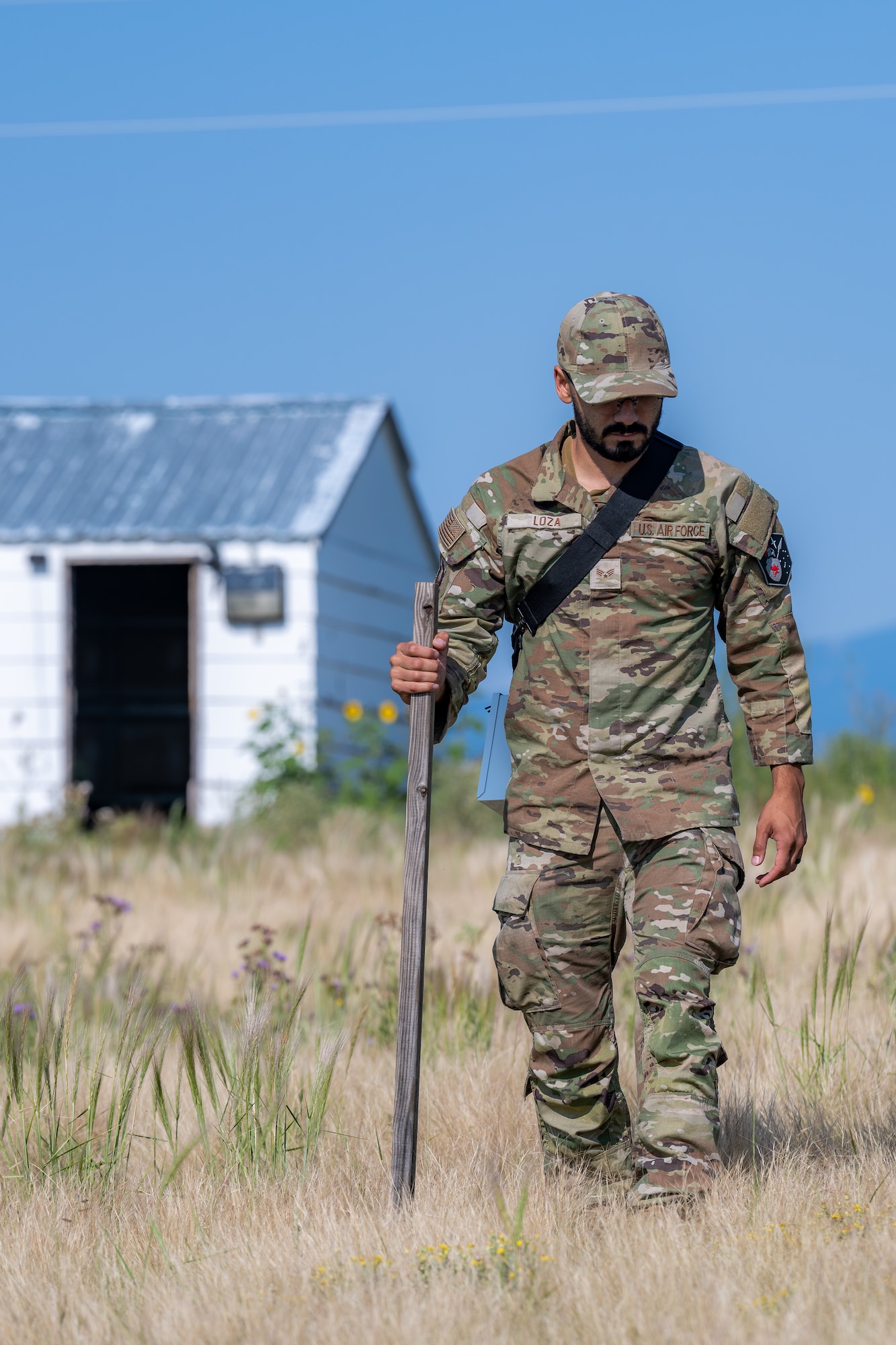 Senior Airman Andrew Loza assists members of the Traditional Cultural Places Survey in surveying open fields.