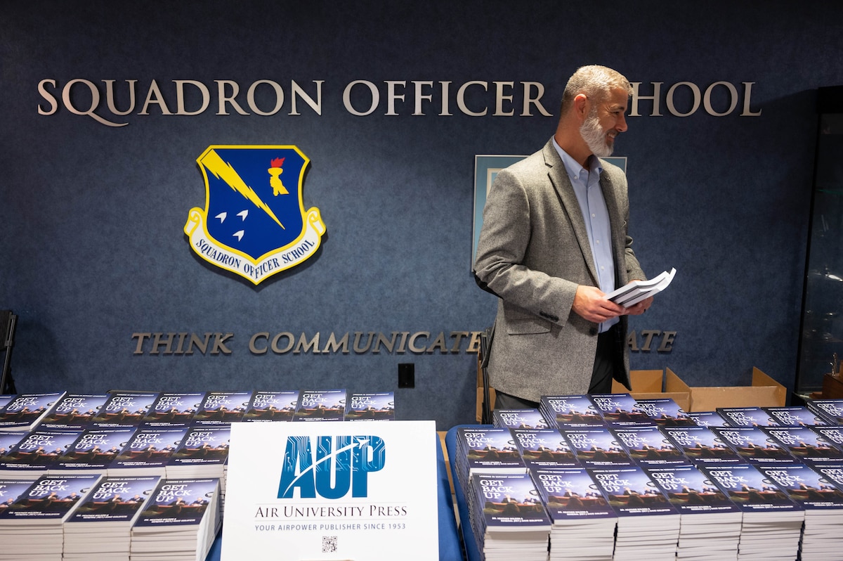 Mike Tate, Aether and Air and Space Operations editor, hands out the book “Get Back Up: Lessons in Servant Leadership” at a fireside chat at the Squadron Officer School on Maxwell Air Force Base, Alabama, Sept. 29, 2025.