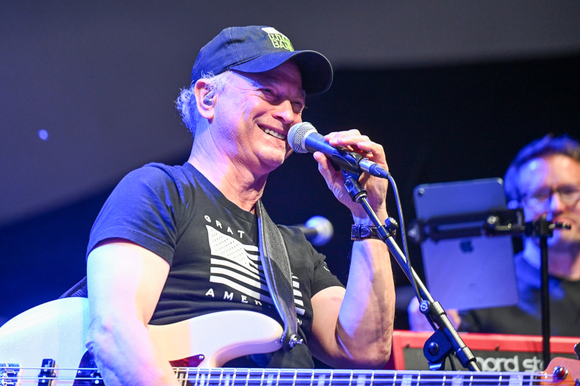 Gary Sinise introduces the performers standing at a microphone.