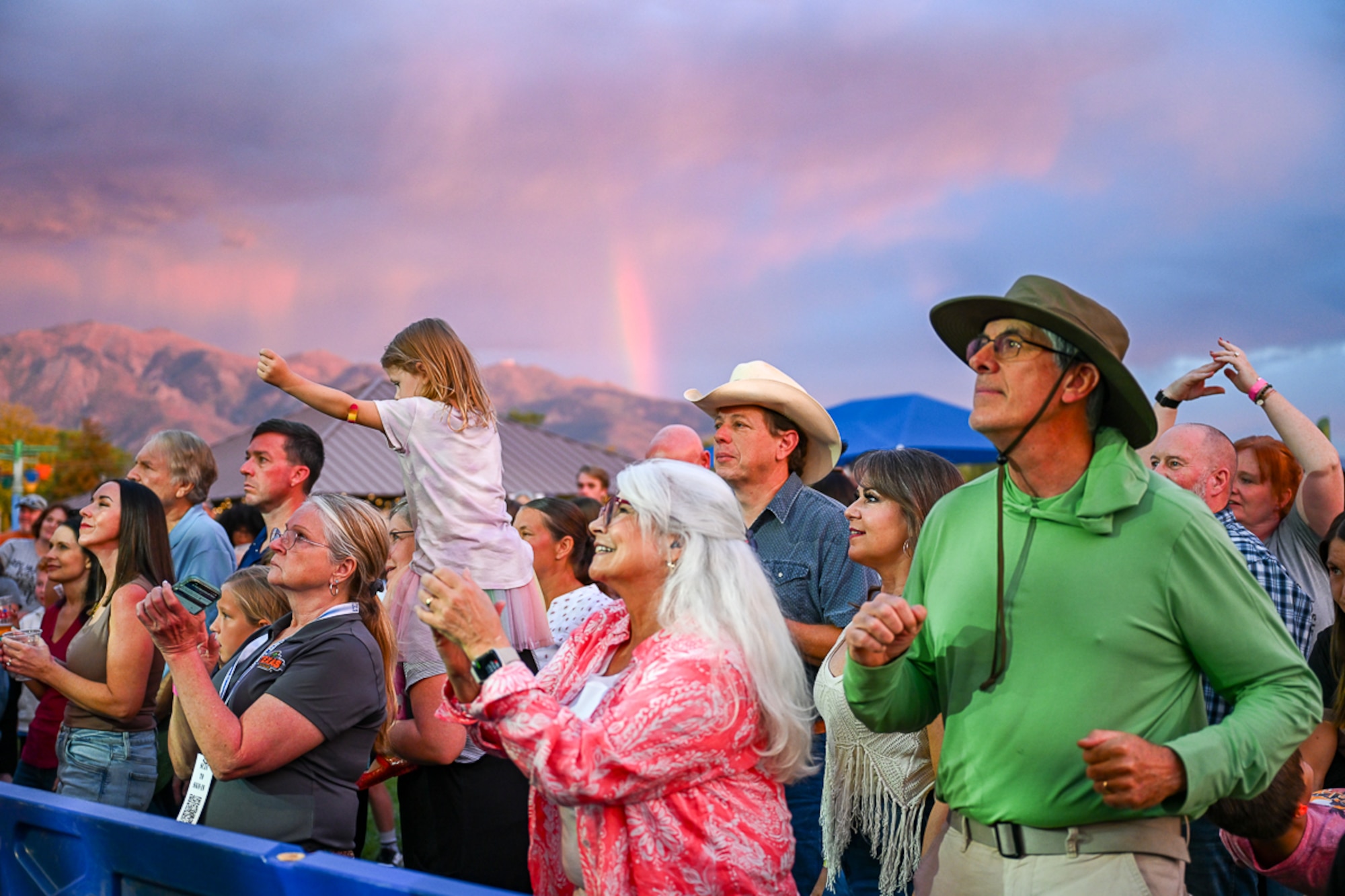 The crowd dances during the Lt. Dan Band’s performance while clouds and rainbow appear in the background.