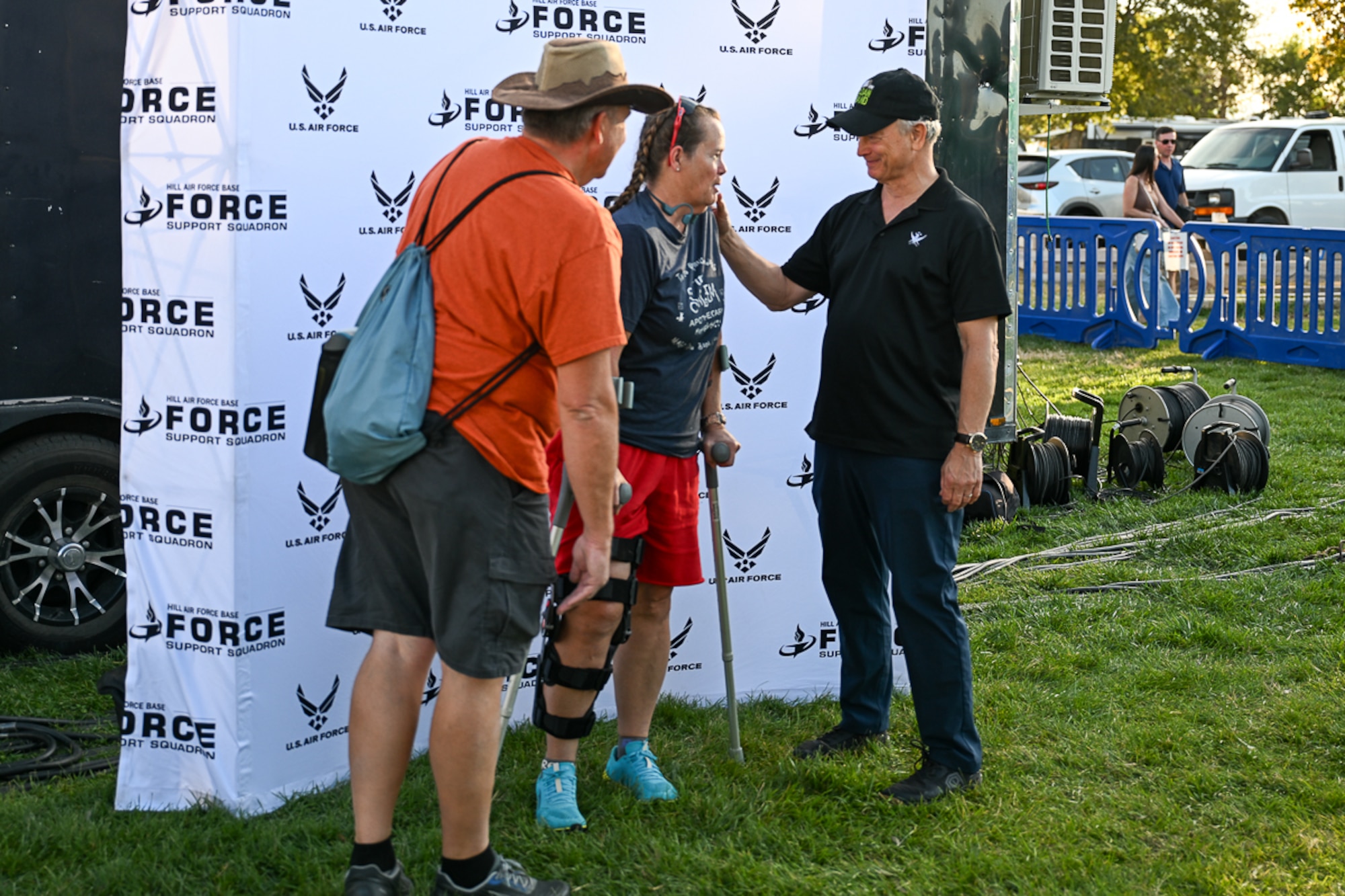 Gary Sinese talking with a couple in front of an Air Force backdrop.