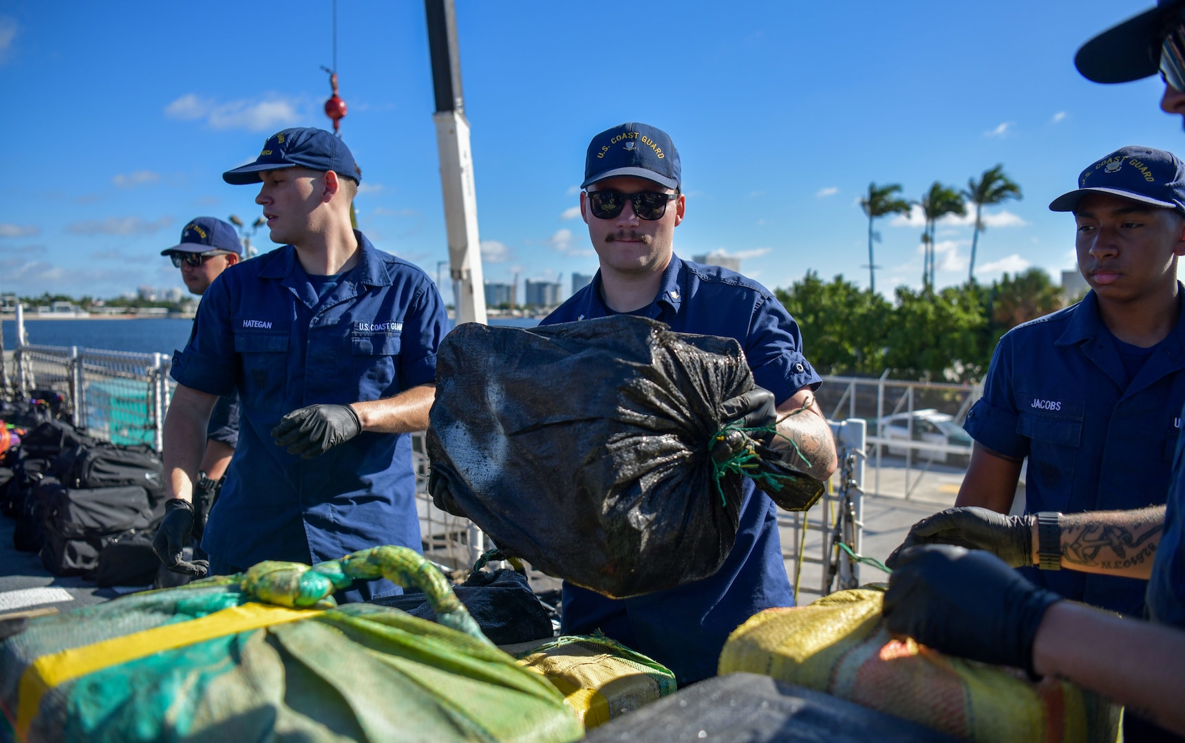 Crew members aboard USCGC Seneca (WMEC 906) stack bales of illicit narcotics on pallets to be offloaded at Port Everglades in Fort Lauderdale, Florida, Sept. 30, 2025. The crew offloaded more than 12,750 pounds of cocaine and marijuana with an approximate street value of $94.5 million. (U.S. Coast Guard photo by Petty Officer 1st Class Diana Sherbs)