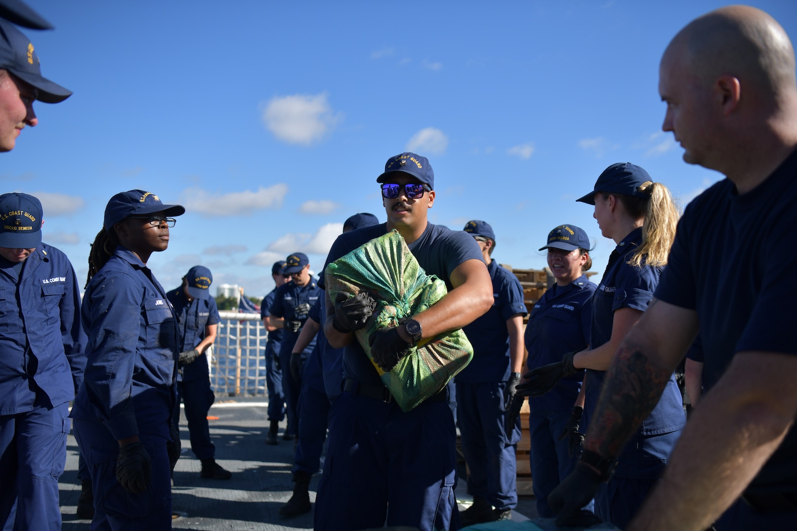Crew members aboard USCGC Seneca (WMEC 906) stack bales of illicit narcotics on pallets to be offloaded at Port Everglades in Fort Lauderdale, Florida, Sept. 30, 2025. The crew offloaded more than 12,750 pounds of cocaine and marijuana with an approximate street value of $94.5 million. (U.S. Coast Guard photo by Petty Officer 1st Class Diana Sherbs)