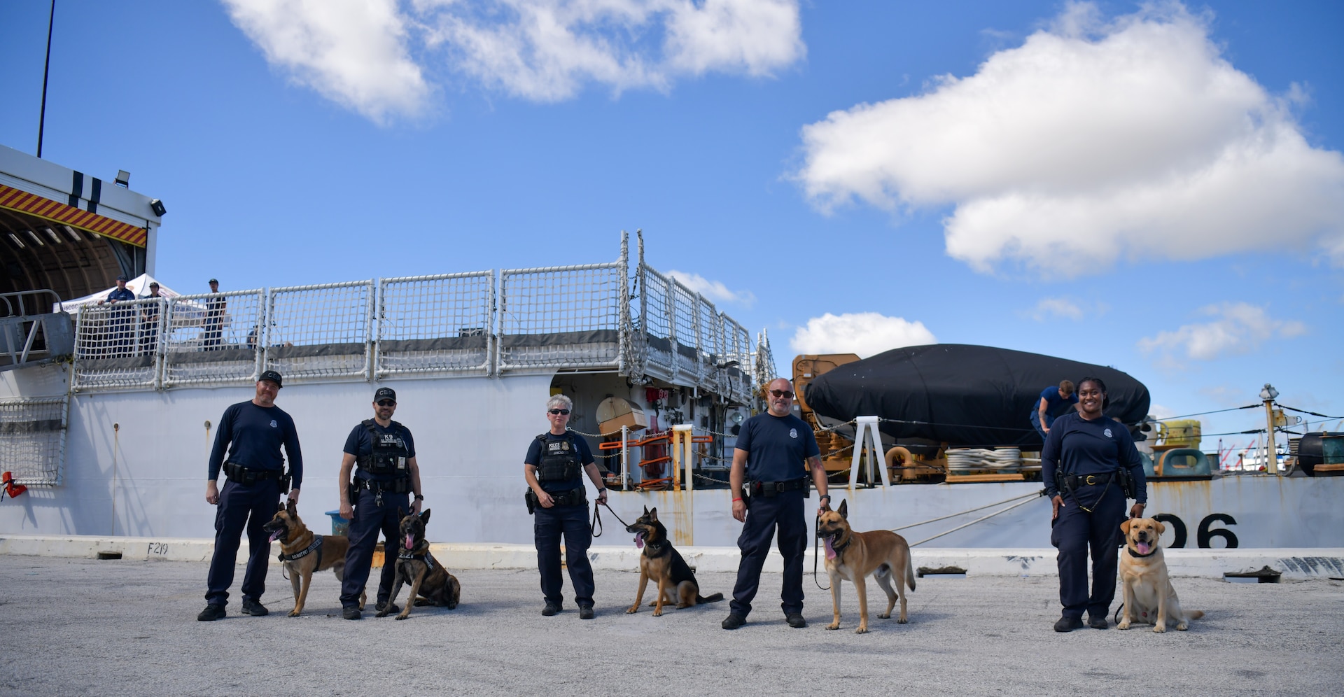 Five U.S Customs and Border Protection canines and their handlers pause for a photo during a drug offload with USCGC Seneca (WMEC 906) at Port Everglades in Fort Lauderdale, Florida, Sept. 30, 2025. The canines conducted drug sniffing tests on offloaded bales of cocaine and marijuana interdicted in the Eastern Pacific Ocean. (U.S. Coast Guard photo by Petty Officer 1st Class Diana Sherbs)