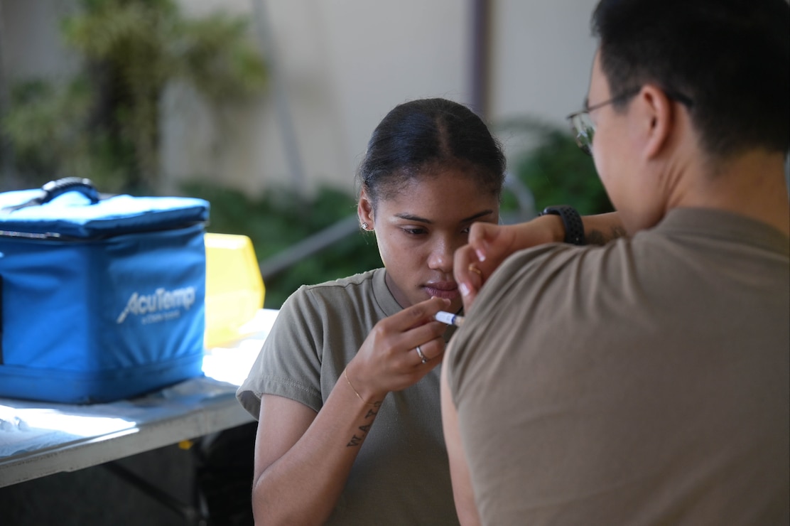 An Airman inserting a syringe into a patient.