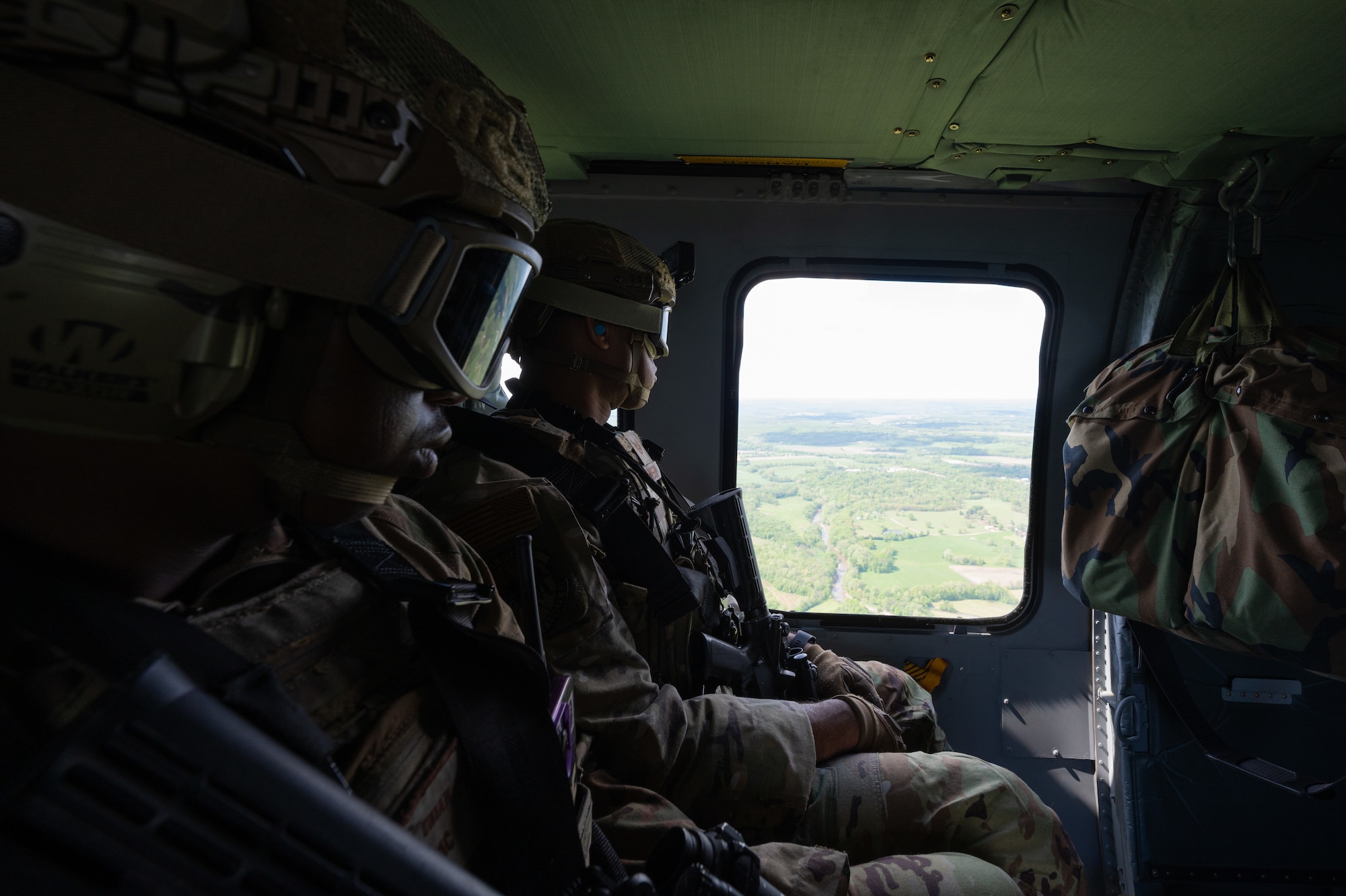 U.S. Air Force Airman 1st Class Uriah Kemp, left, and Staff Sgt. Malachi Sampson, 509th Security Forces Squadron Base Response Team members, ride in a UH-60 Black Hawk helicopter during a joint force exercise over Sedalia, Missouri, May 4, 2025. The exercise strengthened the defenders capabilities to seek out and secure high-value targets and operate in a joint force environment. (U.S. Air Force photo by Senior Airman Joseph Garcia)