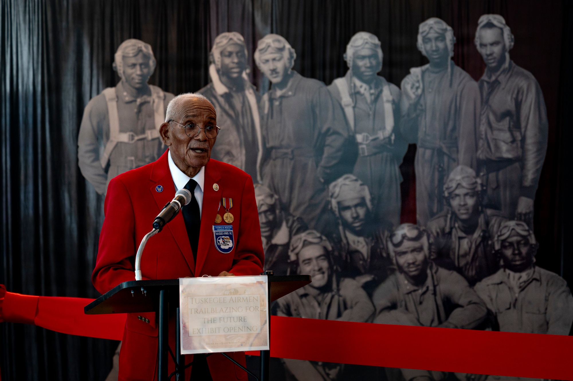U.S. Army Air Corps Sgt. (former) Thomas Newton speaks about his time as a Tuskegee Airman during the grand opening of the new Tuskegee Airmen exhibit at the Virginia Air and Space Science Center in Hampton, Virginia, March 26, 2026. Newton is one of the last living members of the original Tuskegee Airmen whose service contributed to their legacy as the best aviators of their generation. (U.S. Air Force photo by Staff Sgt. Michael Bowman)