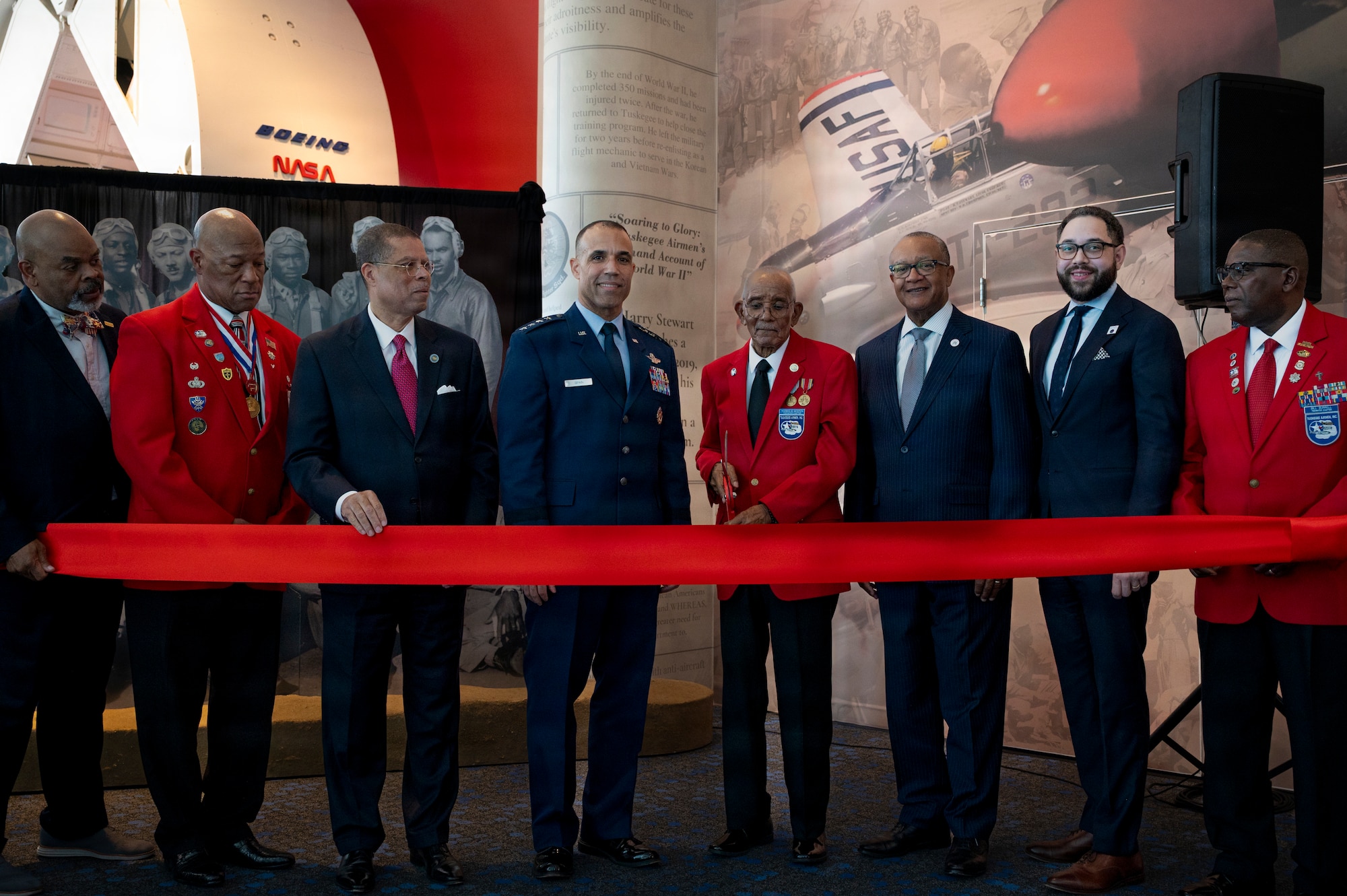 U.S. Air Force Gen. Adrian Spain, commander of Air Combat Command, (center) and other distinguished presenters, to include a Documented Original Tuskegee Airman, cut the ceremonial ribbon during the grand opening of the new Tuskegee Airmen exhibit at the Virginia Air and Space Science Center in Hampton, Virginia, March 26, 2026. The exhibit features a mural, life-sized photographs of the Tuskegee Airmen, an electronic tour guide, and squadron memorabilia, connecting visitors to the legacy of America’s combat air forces. (U.S. Air Force photo by Staff Sgt. Michael Bowman)
