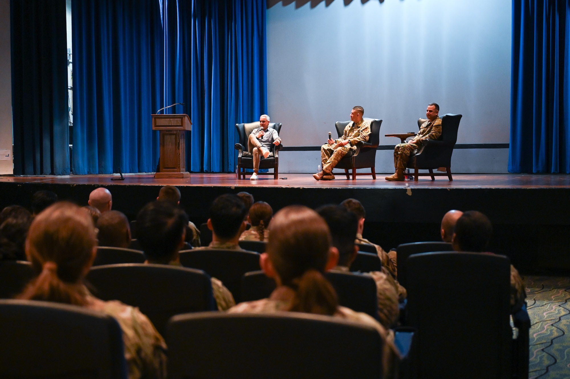 Three people sit on a stage