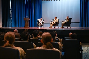 Three people sit on a stage
