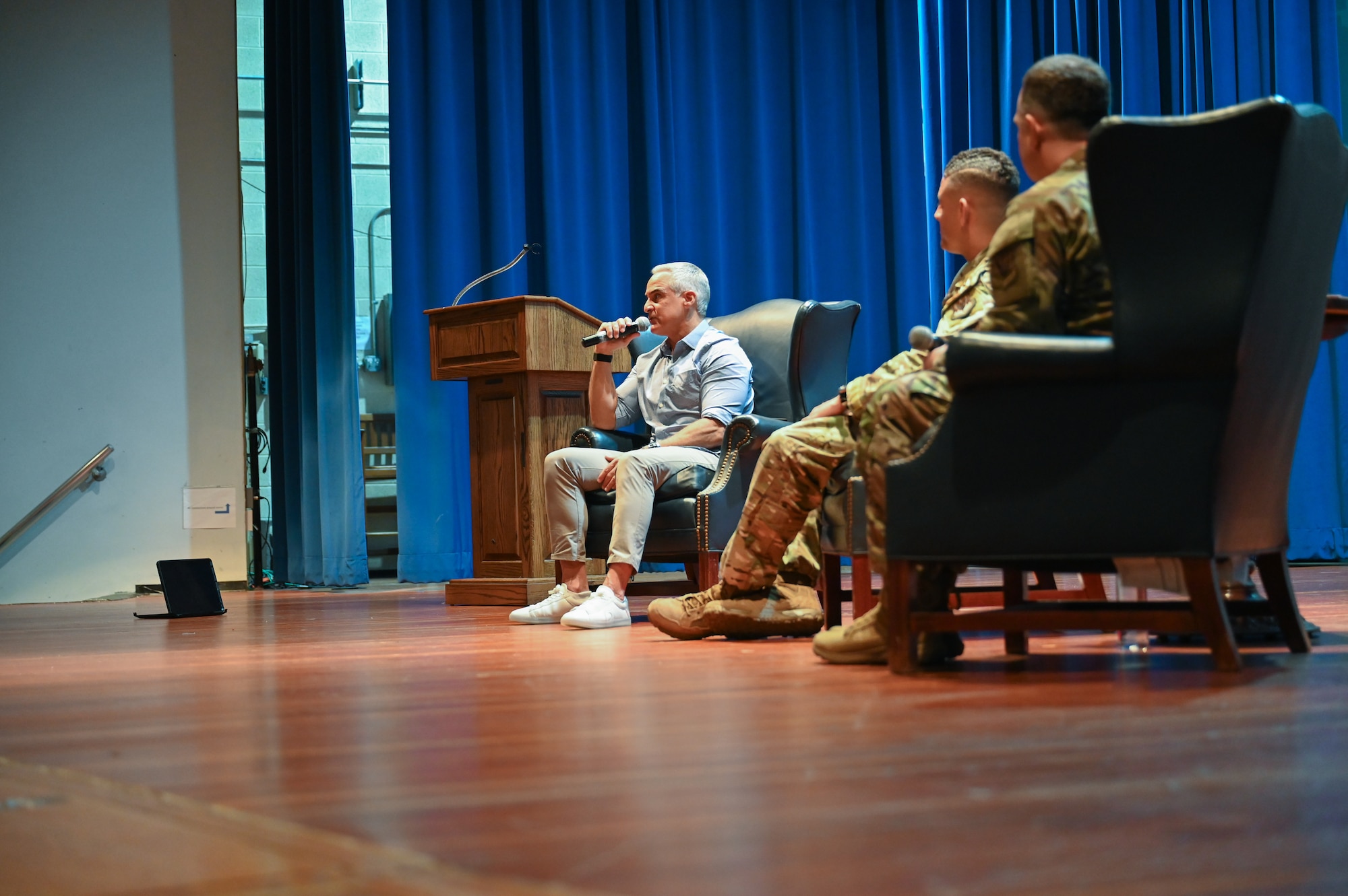 Three people sit on a stage