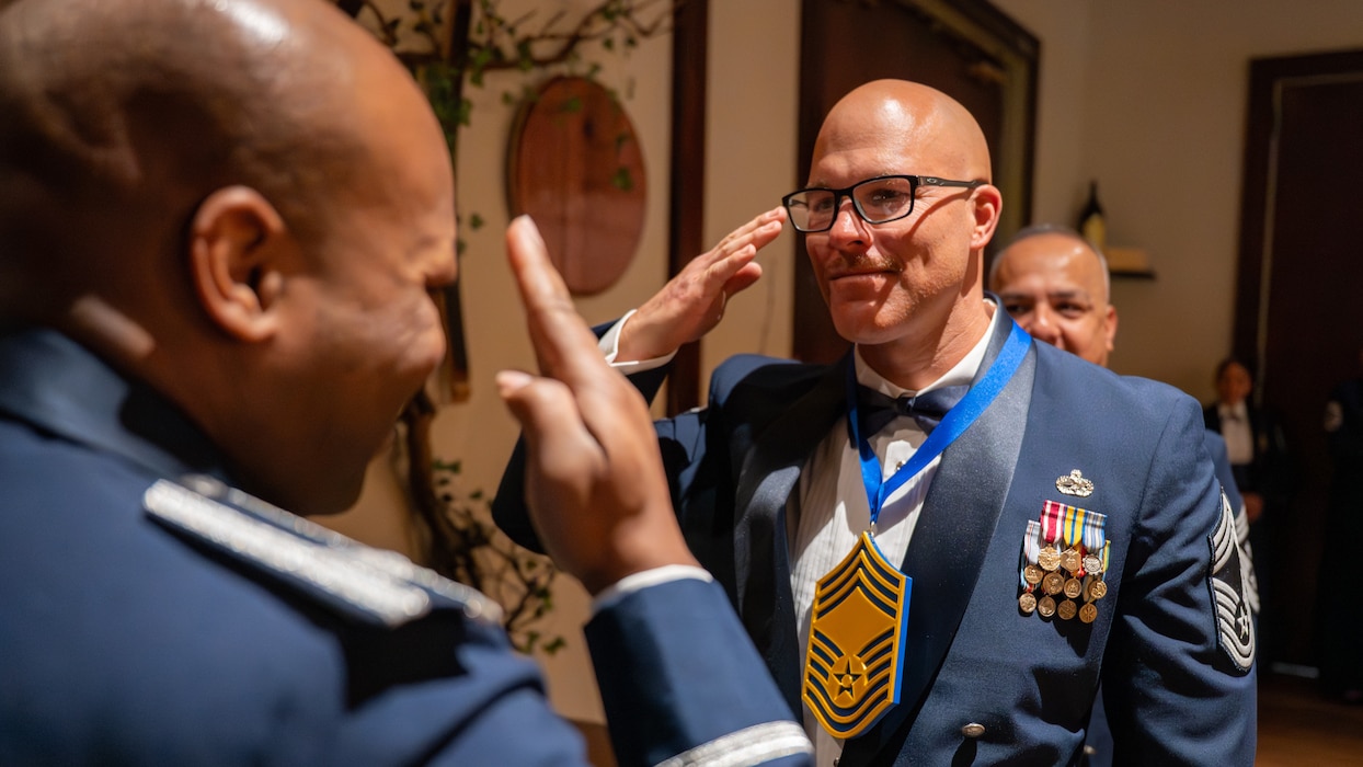 A Chief is visible to the right of frame saluting a Col. to the left of frame and closer to the viewer