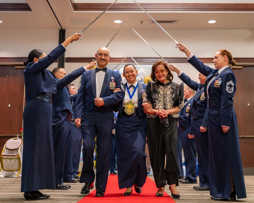 A Chief and her parents are visible in the center of the frame walking through the cordon of honor while smiling