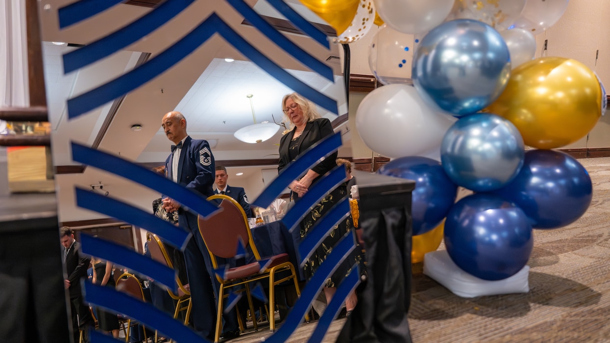 A Chief is seen praying in the reflection of a large mirrored Chief rank insignia