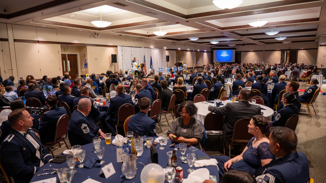 A wide shot shows a full room of Chiefs and family attending the ceremony