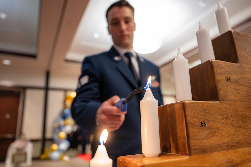 Candle being lit is in focus with the Airman lighting it out of focus behind