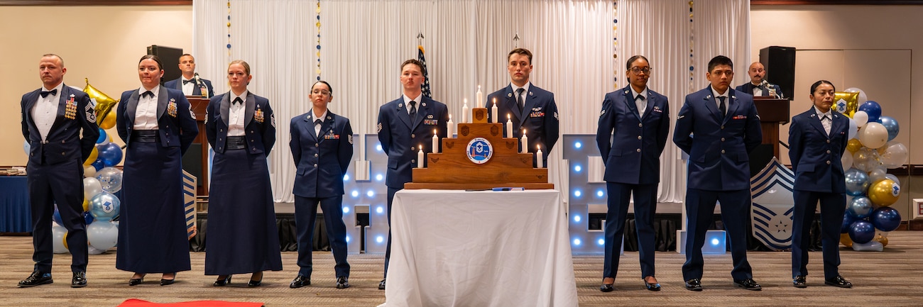 Airmen stand in formation behind a ceremonial candle