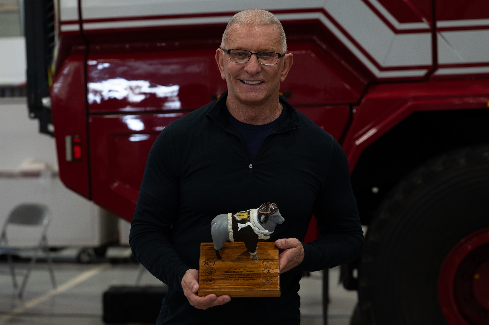 Chef Robert Irvine, a celebrity culinary chef, poses for a photo with thank you gift at the Louis F. Garland Fire Academy, Goodfellow AFB, Texas, March 6, 2026. U.S. Air Force Col. Matthew Norton, 17th Training Wing commander, presented Irvine with the sheep during a Breaking Bread with Heroes Luncheon, and thanked him serving those who serve.