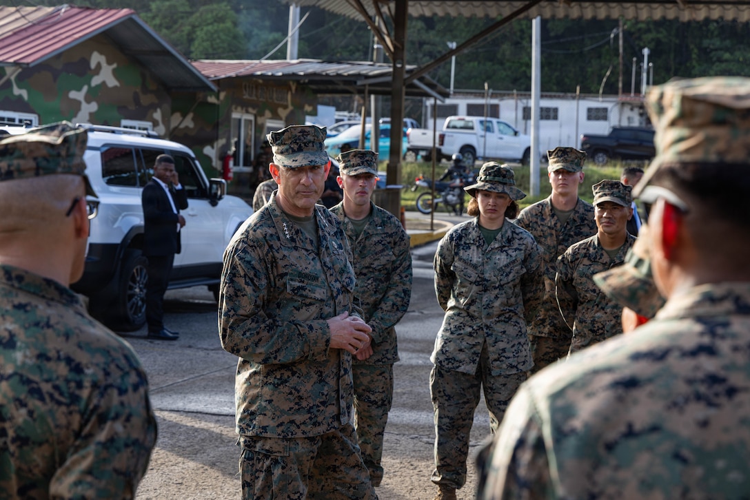 A group of military personnel stand and talk.