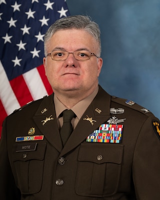 Headshot of Kelvin Mote, USAWC staff, smiling against a neutral background and American Flag.