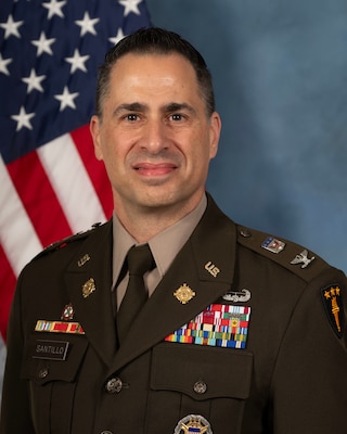 Headshot of Don Santillo, USAWC staff, smiling against a neutral background and American Flag.