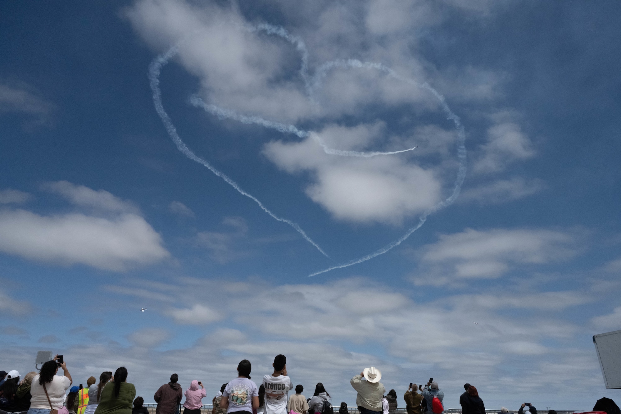 Spectators look above towards a heart-shaped smoke trail during the 2026 Fiesta of Flight airshow at Laughlin Air Force Base, Texas, March 28, 2026. Over 10,000 guests attended this year’s Fiesta of Flight, which featured aerial and static displays, a STEM expo, food vendors, merchandise booths and activities for children. (U.S. Air Force photo by Airman 1st Class Darryl Keith)