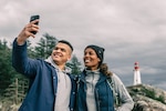 Man and woman take a selfie in front of a lighthouse