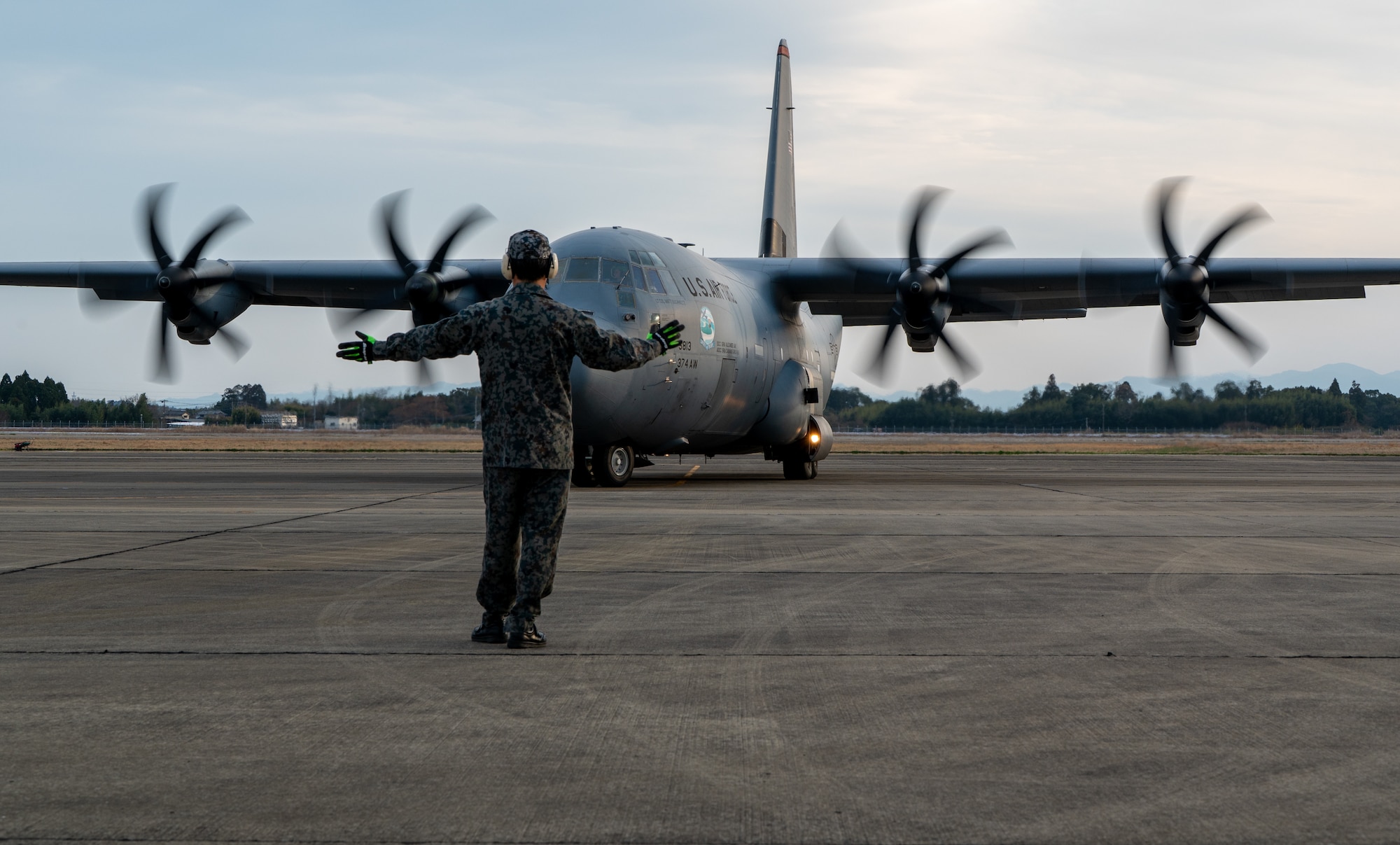 A Japan Air Self-Defense Force member marshals a U.S. Air Force C-130J Super Hercules assigned to the 36th Airlift Squadron, Yokota Air Base, at Japan Air Self-Defense Force Nyutabaru Air Base.