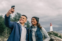 Man and woman take a selfie in front of a lighthouse