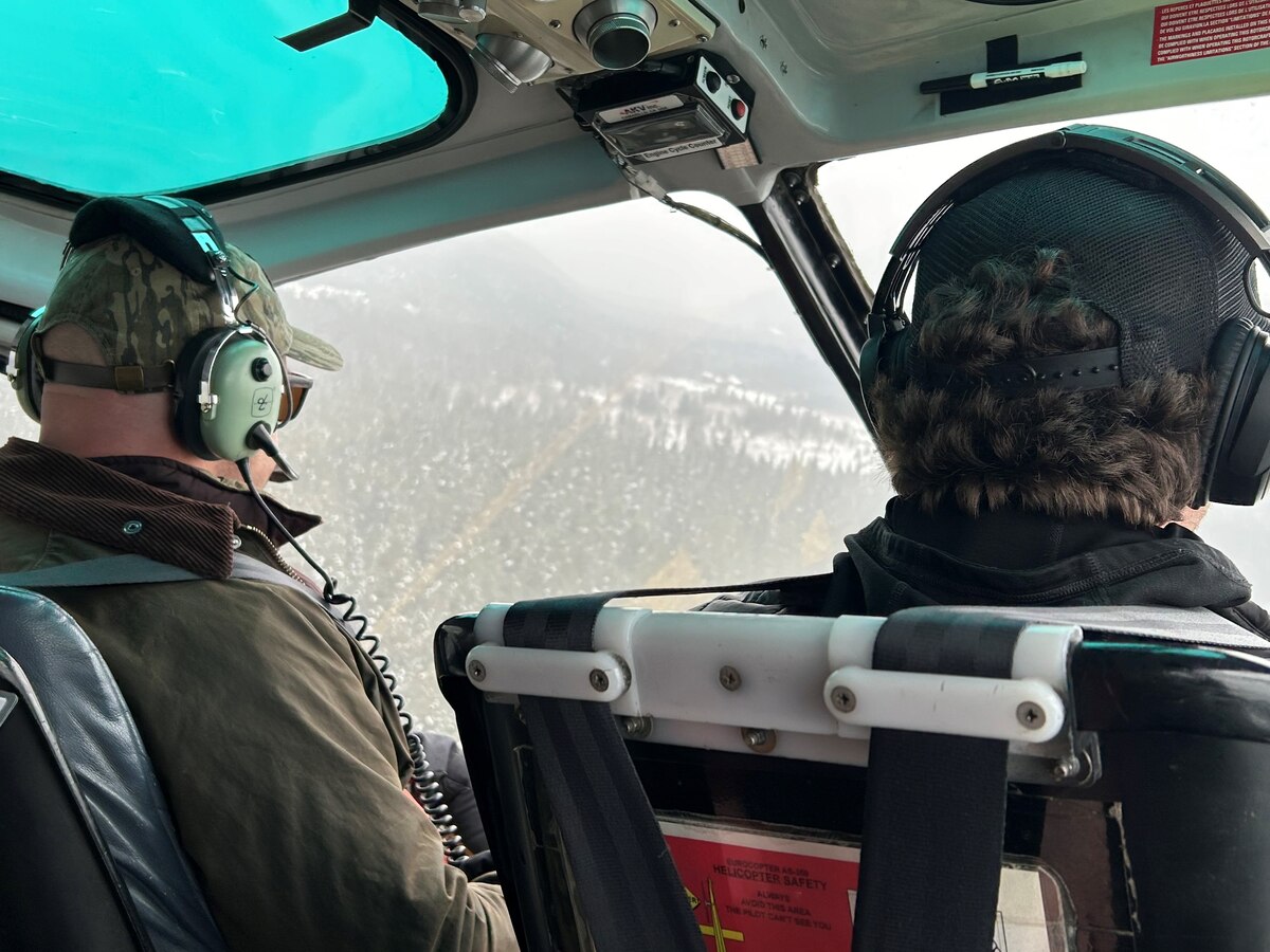 Two people wearing headsets fly in a helicopter.