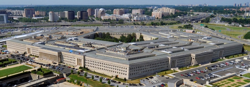 An aerial, daylight view looking down on a large, five-sided building with a large courtyard in the background.