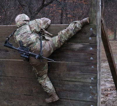 Spc. Dayanara Islas climbs a wall during the 233rd’s "Road to War" training at Marseilles Training Area