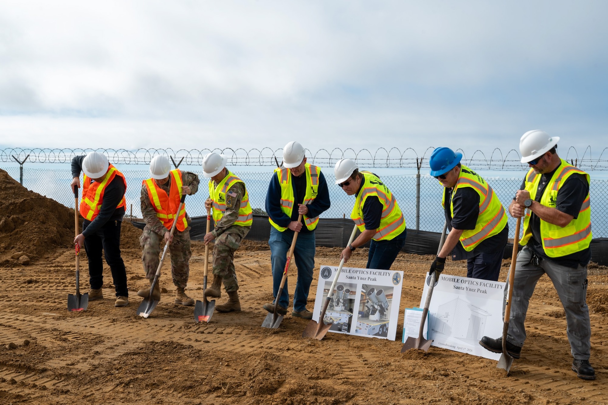 a group of people dig into dirt with shovels