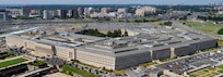 An aerial, daylight view looking down on a large, five-sided building with a large courtyard in the background.