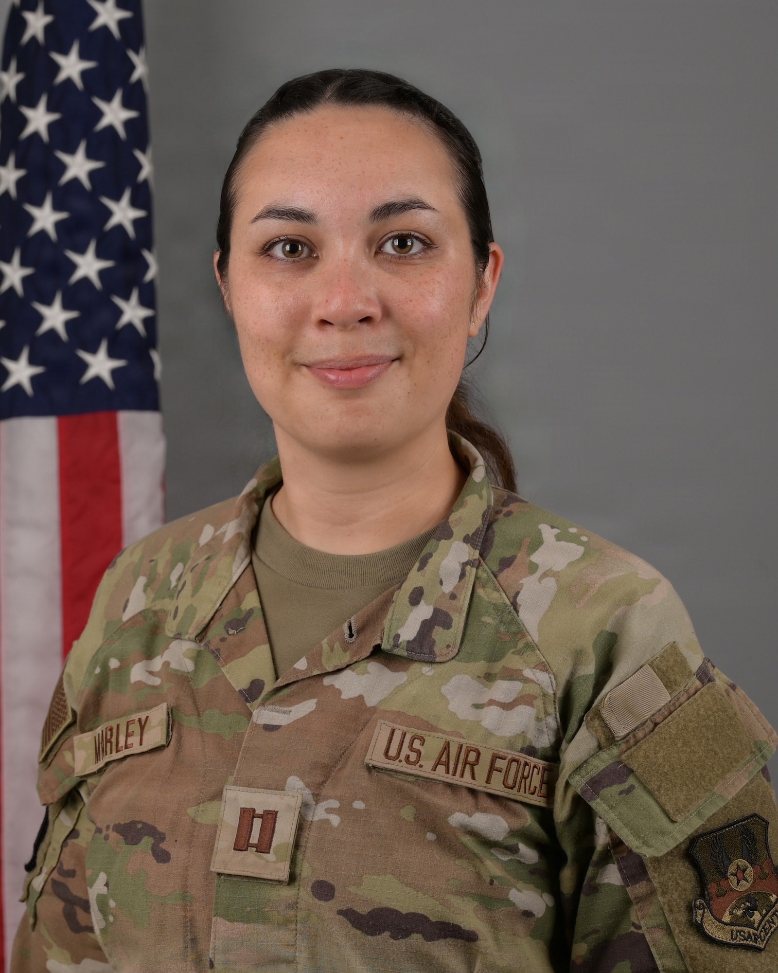 A portrait of a female in a military uniform with an american flag over her right shoulder, or left of the frame
