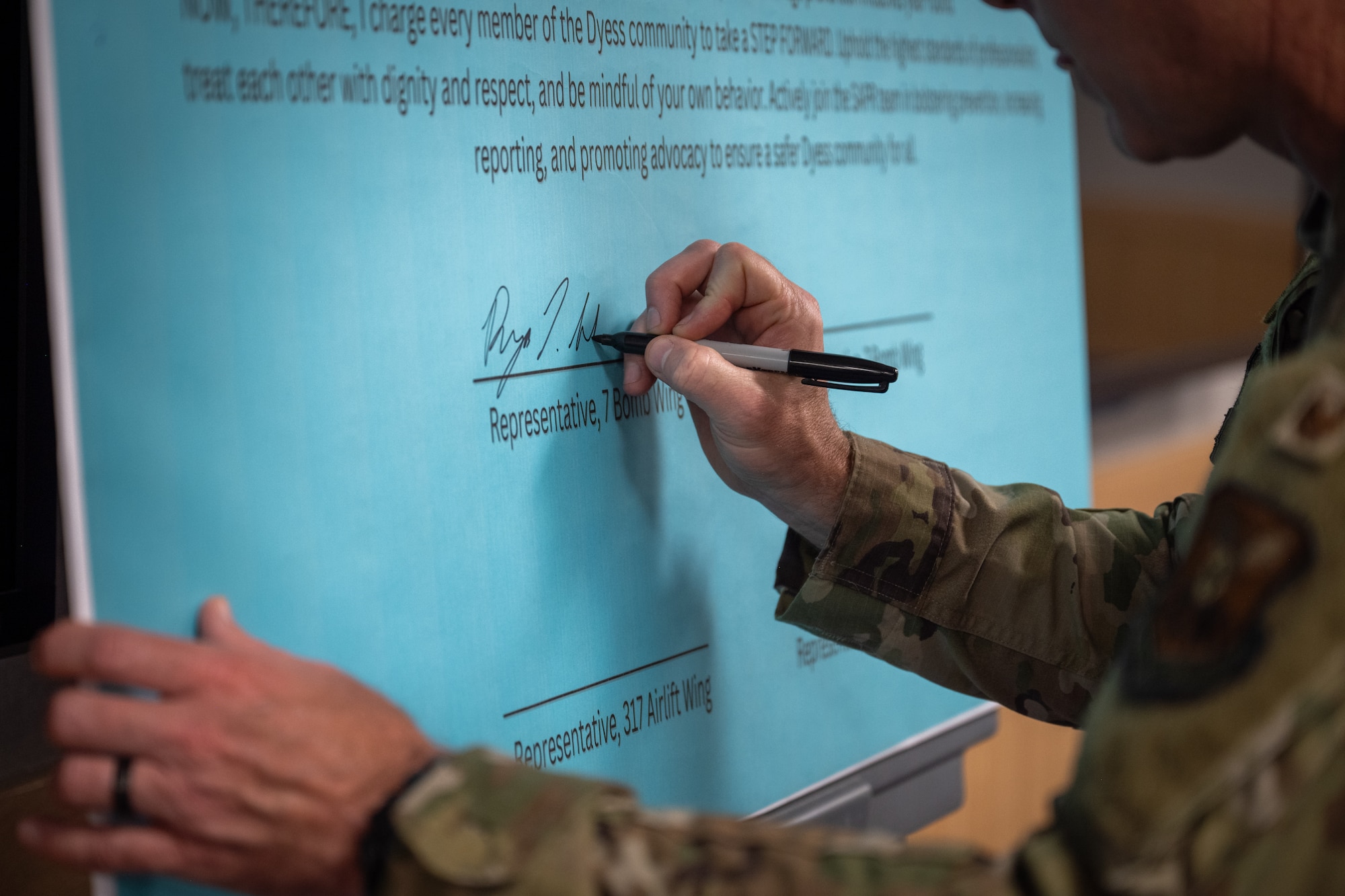 U.S. Air Force Col. Ryan Stallsworth, 7th Bomb Wing deputy commander, signs the Sexual Assault Awareness proclamation at Dyess Air Force Base, Texas, April 1, 2026. Event attendees were invited to add their signatures to the proclamation to demonstrate their support for SAAM. (U.S. Air Force photo by Airman 1st Class Adrien Tran)