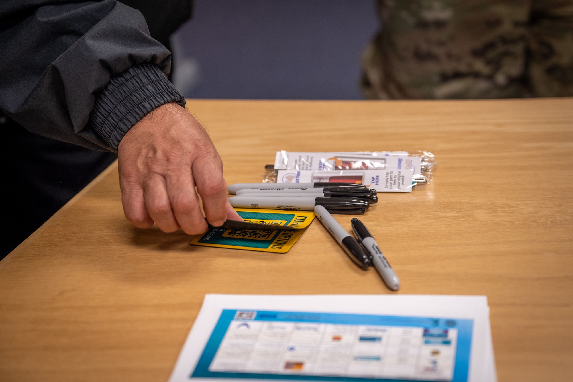 Carlos Duchesne, 7th Bomb Wing Integrated Resilience Office prevention and response director, picks up a magnet during the Sexual Assault Awareness Month proclamation signing at Dyess Air Force Base, April 1, 2026. The event provided informational materials and resources from the Sexual Assault Prevention and Response office. (U.S. Air Force photo by Airman 1st Class Adrien Tran)