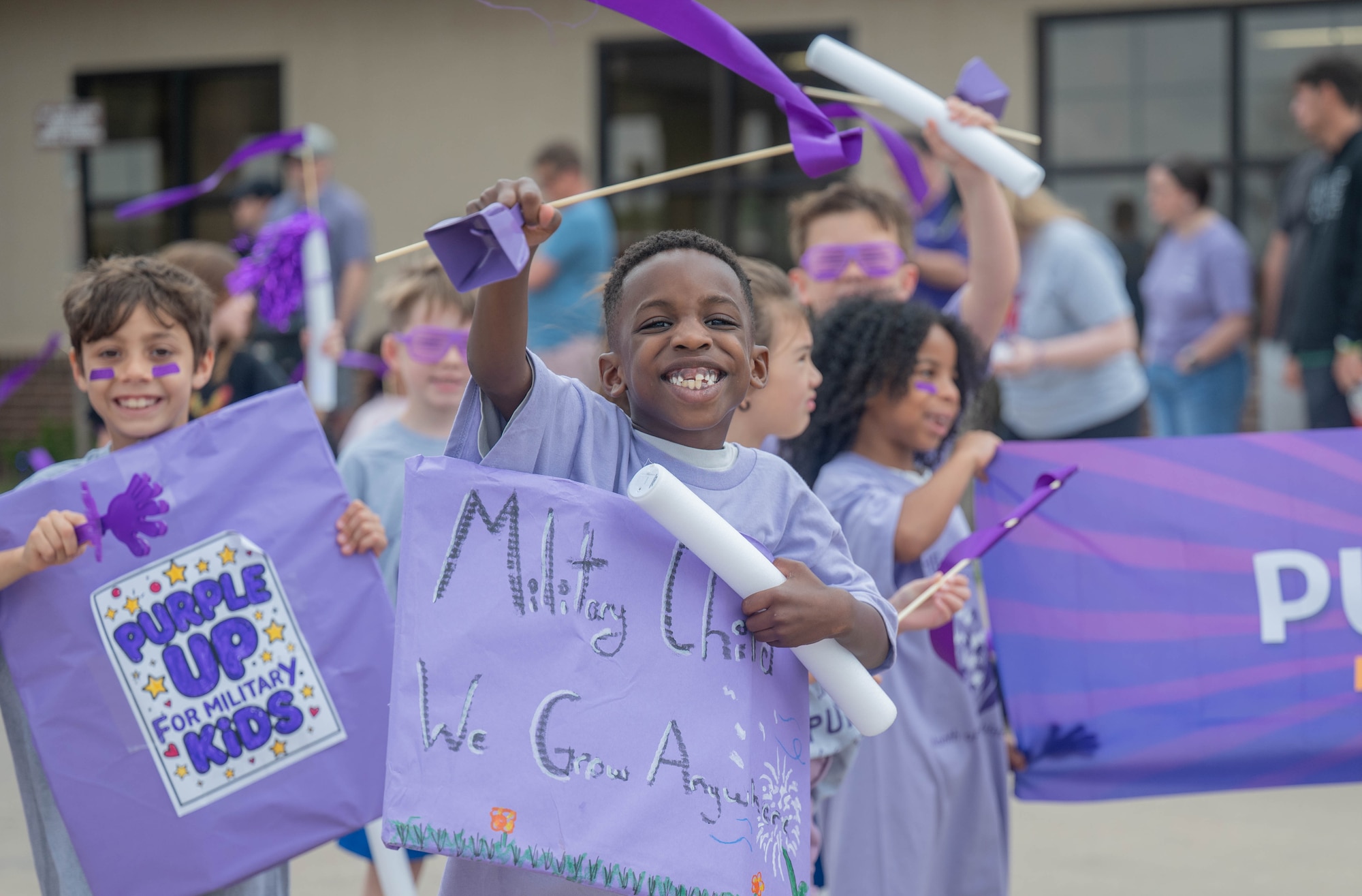 A child holds a sign and smiles during a celebratory parade to honor the Month of the Military Child at Altus Air Force Base, Oklahoma, April 3, 2026. The Month of the Military Child highlights the important role military children play in supporting their families and the mission. (U.S. Air Force photo by Airman 1st Class Emma Wright)
