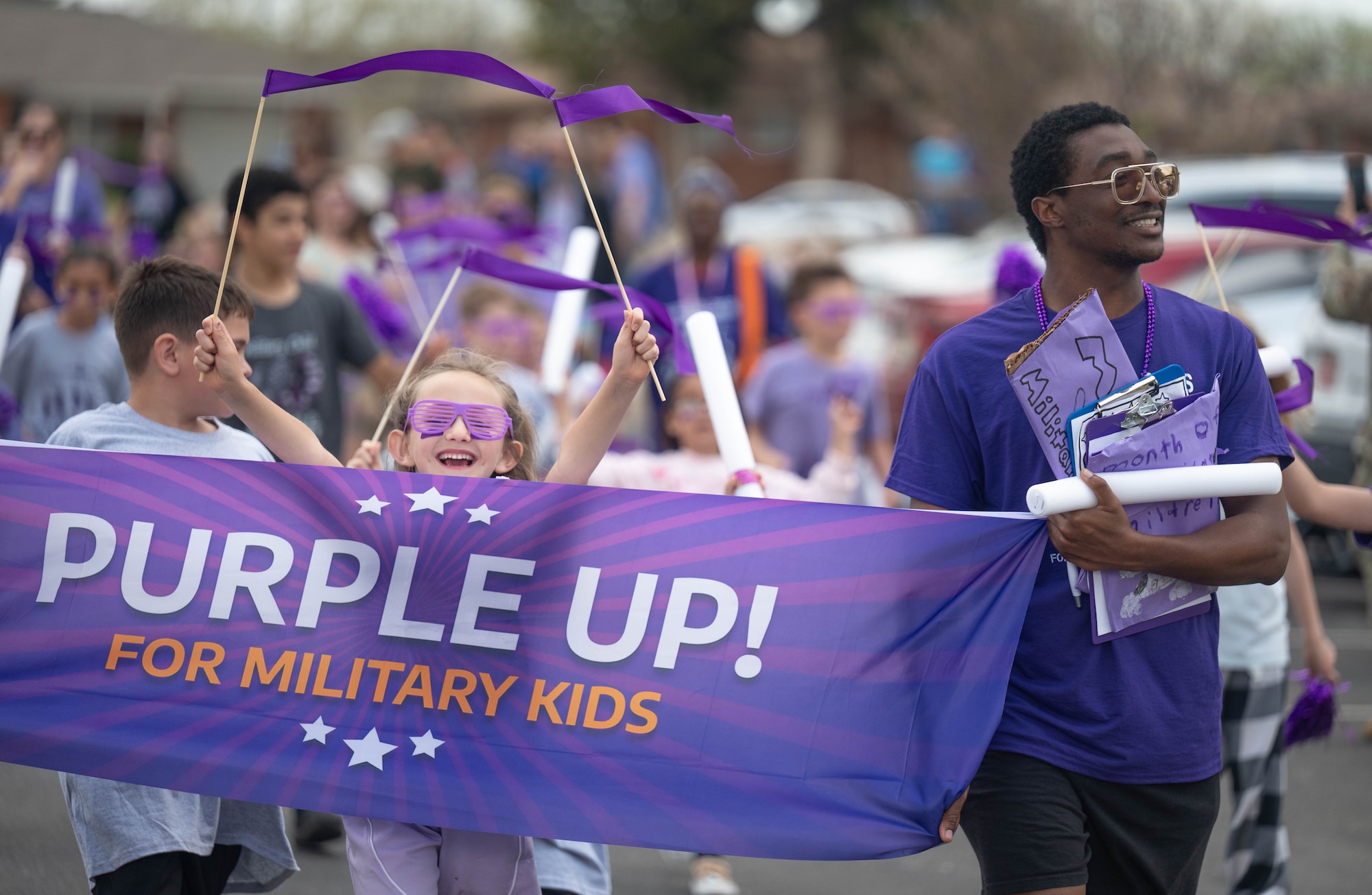 A child holds purple ribbons and smiles during a celebratory parade to honor the Month of the Military Child at Altus Air Force Base, Oklahoma, April 3, 2026. The Month of the Military Child emphasizes the resilience and commitment of children who support their families in service. (U.S. Air Force photo by Airman 1st Class Emma Wright)