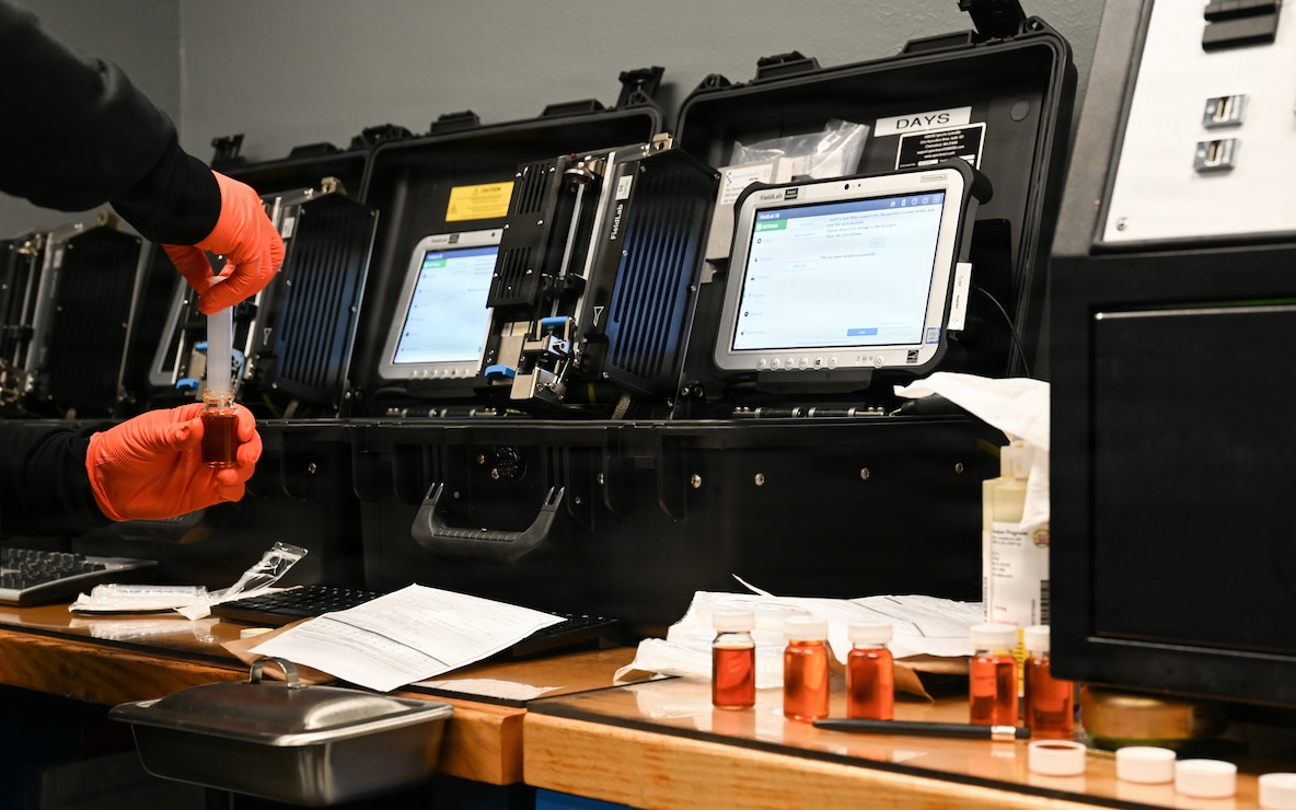An Airman draws oil into a sampling device.