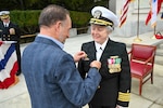 BETHESDA, Md. (Apr. 2, 2026) Capt. Darla Dietrich, commanding officer of Navy Medicine Readiness and Training Command (NMRTC) Bethesda, is adorned with the command pin by her husband during a combined change of command and retirement ceremony, at Walter Reed National Military Medical Center, Apr. 2, 2026. NMRTC Bethesda’s mission is to maximize warfighter performance through optimized medical readiness tailored to operational requirements; enhance the readiness of the medical force to sustain expeditionary medical capability; and train and develop the Navy Medicine Force. (U.S. Navy photo Mass Communication Specialist Second Class Alec Kramer)