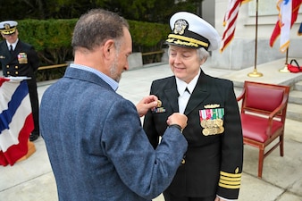BETHESDA, Md. (Apr. 2, 2026) Capt. Darla Dietrich, commanding officer of Navy Medicine Readiness and Training Command (NMRTC) Bethesda, is adorned with the command pin by her husband during a combined change of command and retirement ceremony, at Walter Reed National Military Medical Center, Apr. 2, 2026. NMRTC Bethesda’s mission is to maximize warfighter performance through optimized medical readiness tailored to operational requirements; enhance the readiness of the medical force to sustain expeditionary medical capability; and train and develop the Navy Medicine Force. (U.S. Navy photo Mass Communication Specialist Second Class Alec Kramer)