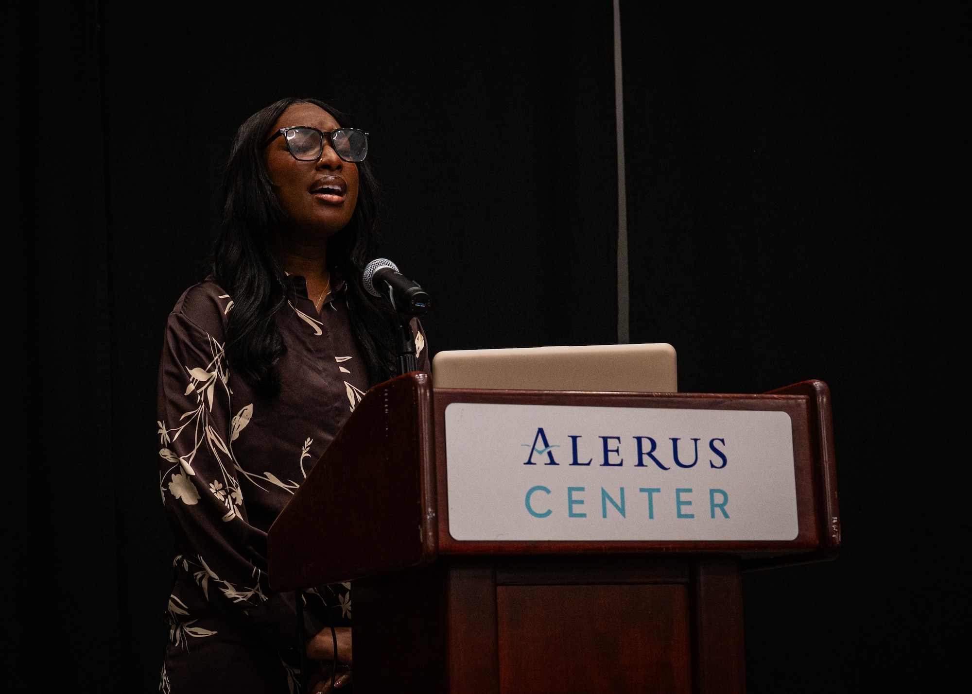 A photo of a woman singing into a microphone.
