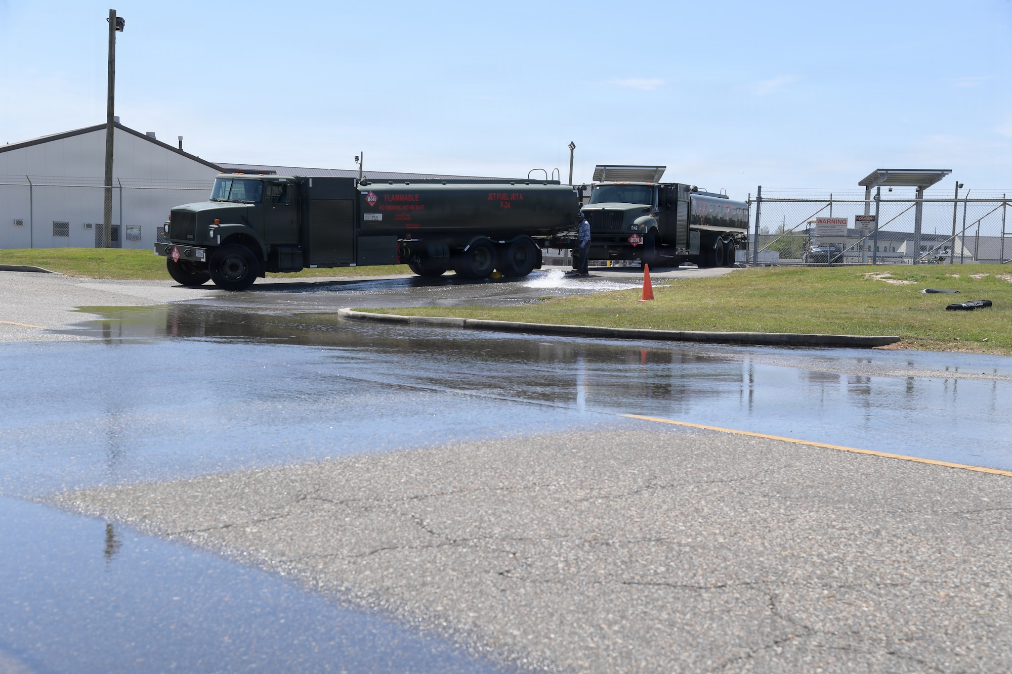 Fuel trucks are parked on the side of a road with water in the roads.