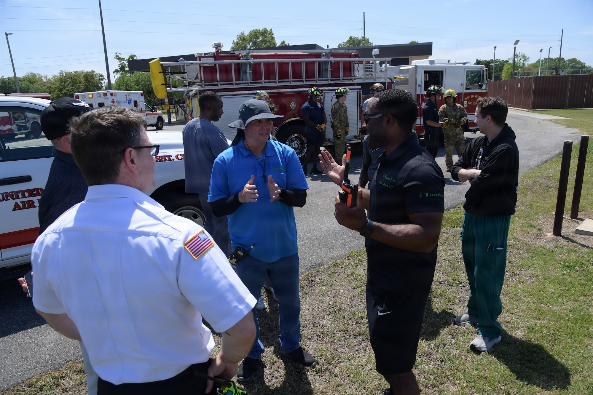A group of emergency responders gather together to discuss the training scenario in front of a fire truck.
